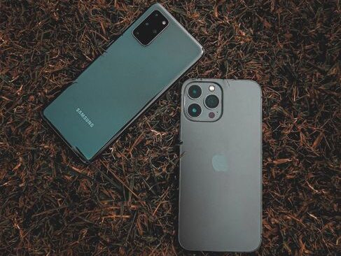 Top view of Samsung and iPhone placed on a grassy surface, showcasing modern smartphone design.